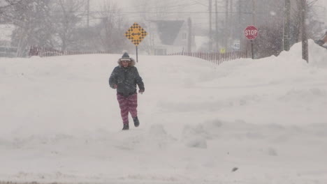 Person-running-in-the-street-covered-in-snow-during-a-snowfall-Blizzard,-Static-shot