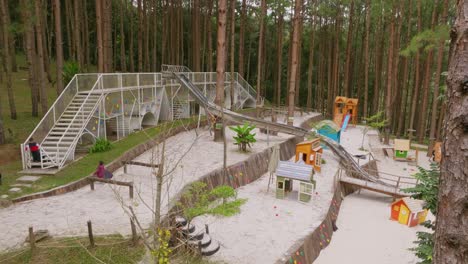 Aerial-tracking-two-kids-playing-on-children's-curved-slide-with-the-ground-lots-of-white-sand