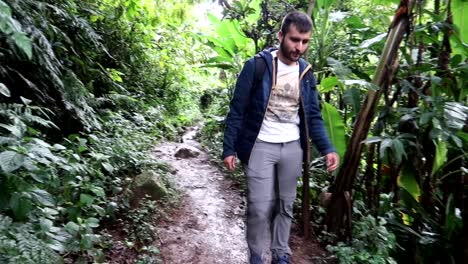 Young-man-walking-through-the-mud-in-a-tropical-green-rainforest-towards-camera