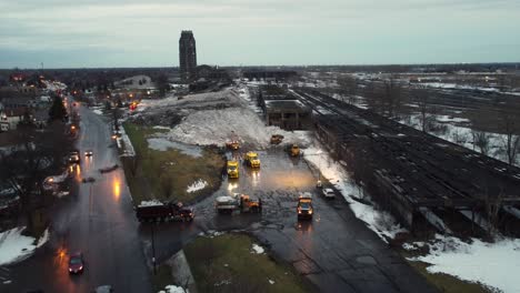 Aerial-view-as-dump-trucks-bringing-in-loads-of-snow-during-blizzard-cleanup-effort,-Buffalo,-New-York,-US
