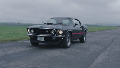 Ford-Mustang-Mach-1-Old-timer-Moviéndose-En-Carretera-Mojada,-Clásico-Coche-Deportivo-Americano