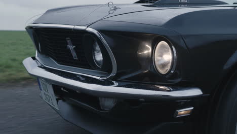 Primer-Plano-Del-Ford-Mustang-Mach-1-Delantero,-Coche-Deportivo-Clásico-Moviéndose-En-La-Carretera