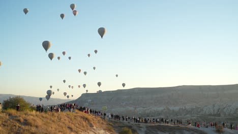 Globos-Aerostáticos-Volando-Sobre-La-Gente-En-La-Colina-Sobre-Capadocia,-Turquía,-Cámara-Lenta