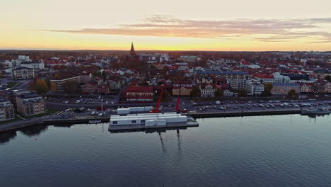Shipyard-for-ferry-shipping-containers-at-Slottsholmen,-Sweden-at-sunrise---aerial-flyover