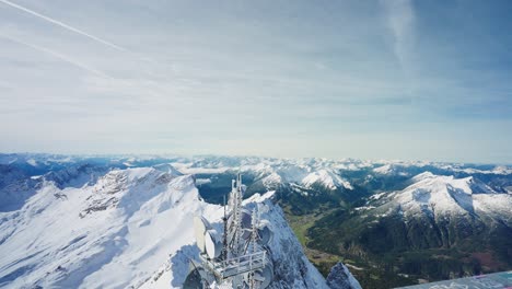 Blick-über-Das-Geländer-Und-Einen-Telefonmast-Auf-Das-Grüne-Tal-Unterhalb-Eines-Schneebedeckten-Berggipfels-In-Den-Alpen