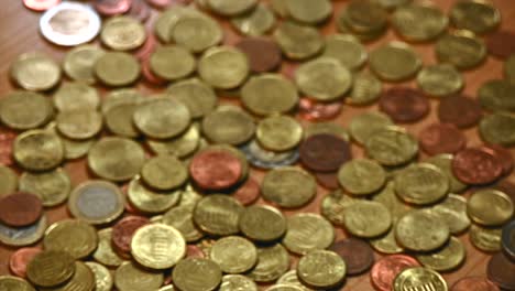 A-variety-of-Euro-and-Canadian-dollar-bills-being-shaken-onto-a-table-covered-in-Euro-coins,-captured-in-a-close-up-shot