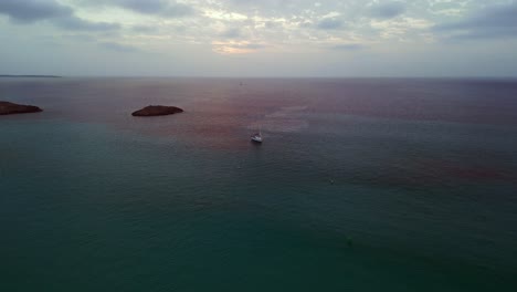 Bewölkter-Himmel,-Einsames-Segelboot-In-Der-Bucht-Bei-Sonnenuntergang