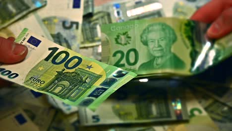 Two-sets-of-white-caucasian-hands-exchanging-Euros-for-Canadian-dollars-on-a-table,-close-up-shot