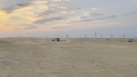 A-white-SUV-drifting-in-circles-in-the-desert-sand-at-sunset