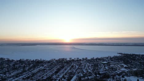 Drone-flying-towards-Lake-simcoe-during-winter-and-golden-hour-sunset