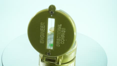Nahaufnahme-Eines-Goldenen-Retro-Kompasses-Auf-Einem-Reflektierenden-Drehständer,-360-Grad,-Grüner-Pfeil,-Studiobeleuchtung,-Zeitlupe,-4k-Video