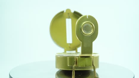 Nahaufnahme-Eines-Goldenen-Retro-Kompasses-Auf-Einem-Reflektierenden-Drehständer,-360-Grad,-Studiobeleuchtung,-Zeitlupe,-4k-Video