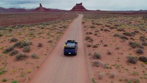 Car-driving-down-road-in-desert,-Valley-of-the-Gods,-Utah,-United-States