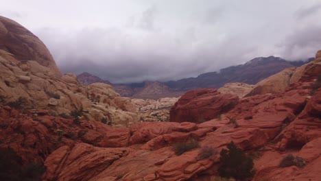 Gimbal-panning-shot-from-heavy-clouds-to-unique-sandstone-formations-in-Red-Rock-Canyon,-Nevada