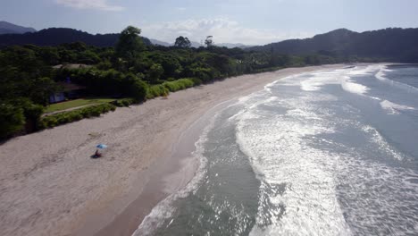 Aerial-view-low-over-waves-at-a-quiet-beach-on-Costa-Verde-in-sunny-Brazil