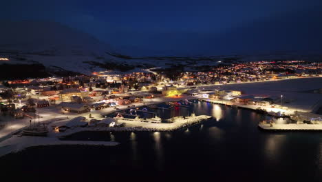 Panorámica-Aérea-Amplia-Toma-De-Drones-Nocturnos-De-Una-Ciudad-Iluminada-En-Islandia-Durante-El-Invierno