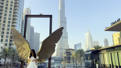 Girl-wearing-a-white-dress-taking-pictures-with-the-Wings-of-Mexico-statue-near-the-tallest-building-in-the-world