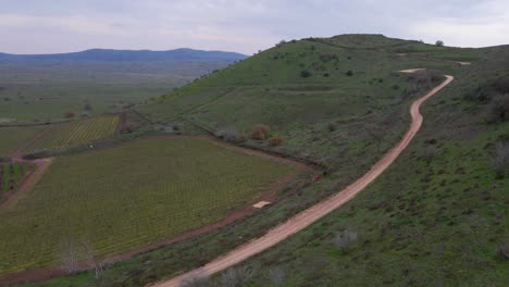Aerial-view-of-rugged-terrain-and-dirt-road-on-Mount-Shifon-slope,-Israel