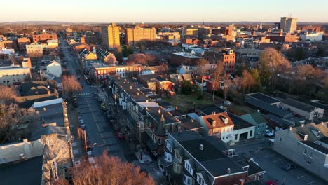 Aerial-rising-shot-of-homes-and-Lancaster,-Pennsylvania-skyline-during-beautiful-golden-hour-sunset-in-winter