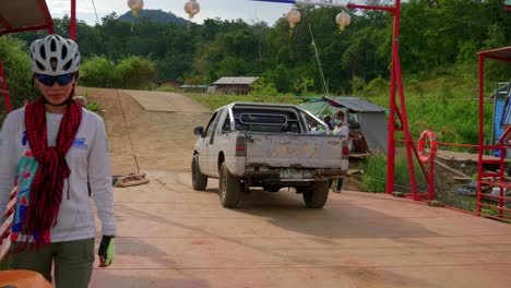 Shot-of-a-white-car-backing-up-onto-a-barge-to-cross-the-water-body-in-Pak-Nai-fisherman-village,-Nan-province,-Thailand-on-a-sunny-day