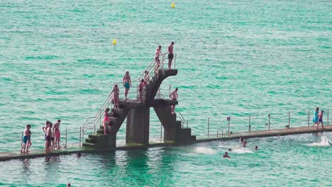 Menschen-Springen-Vom-Sprungbrett-Im-Meerwasserschwimmbad-Am-Plage-De-Bon-secours