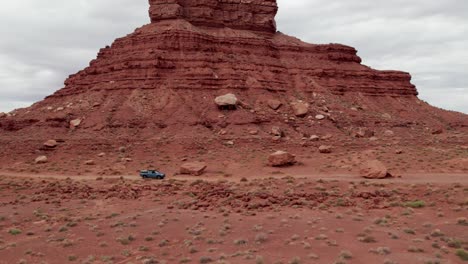 Car-driving-by-Eroded-Rock-Formations,-Valley-of-the-Gods,-Utah,-United-States