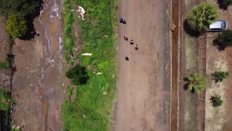 Video-De-Drones-De-Chicos-Caminando-En-Una-Carretera-En-El-Oeste-De-Harare,-Zimbabwe