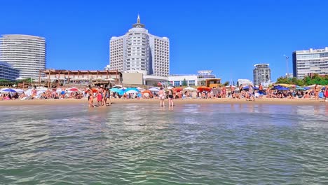 überfüllte-Strände-Vor-Dem-Enjoy-Hotel-Und-Der-Skyline-Von-Punta-Del-Este,-Anfang-Januar-2023,-Während-Der-Hochsaison-In-Uruguay