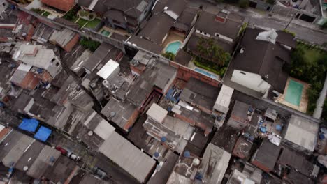 Aerial-view-over-a-favela-and-a-wealthy-area-in-cloudy-Sao-Paulo,-Brazil---tilt,-drone-shot