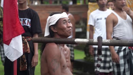 Shirtless-Native-man-from-Bali-dancing-with-a-wooden-poll-on-his-shoulder