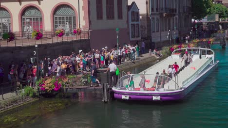 Passengers-disembark-a-half-empty-sightseeing-boat-near-Pont-du-Corbeau,-Strasbourg,-Alsace