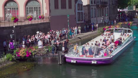 Passengers-board-a-half-empty-sightseeing-boat-near-Pont-du-Corbeau,-Strasbourg,-Alsace,-France