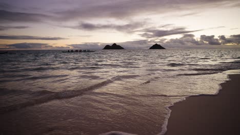 Un-Grupo-De-Canoeros-Remando-Más-Allá-De-Las-Islas-Mokolua-Frente-A-La-Playa-De-Lanikai,-Kailua,-Hawaii-Al-Amanecer-En-Cámara-Lenta