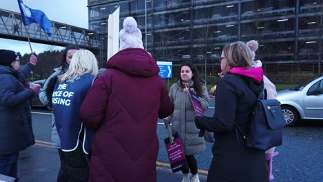 NHS-nurses-strike,-standing-waving-banners-and-flags-demanding-fair-pay-and-better-patient-care