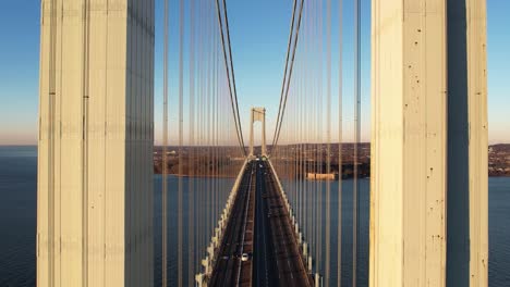 Aerial-view-flying-low-over-traffic-on-the-Verrazzano-Narrows-bridge,-golden-hour-in-NY,-USA
