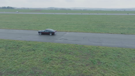 Aerial-View-of-Ford-Mustang-Mach-1,-Classic-Sports-Car-on-the-Road,-Drone-Shot