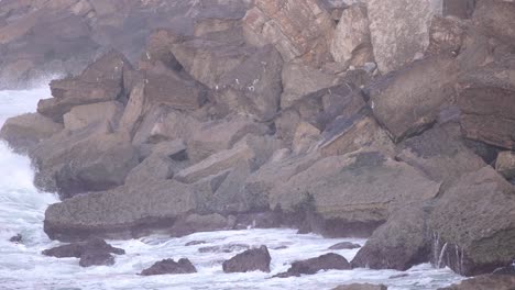 Close-up-view-of-the-strong-waves-in-the-Guincho-area,-with-the-Cabo-Raso-Lighthouse-at-the-top