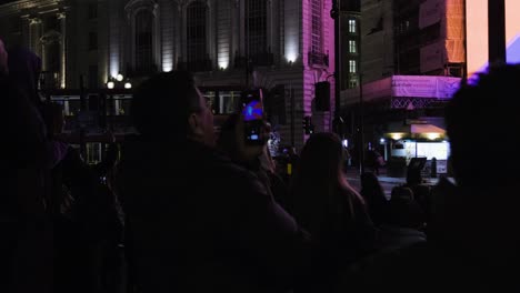 Piccadilly-Circus-Bei-Nacht-In-London-Mit-Leuten,-Die-Den-Bildschirm-Auf-Ihren-Handys-Beobachten-Und-Aufzeichnen