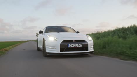 White-Nissan-GRT-speeding-on-countryside-road-at-sunset