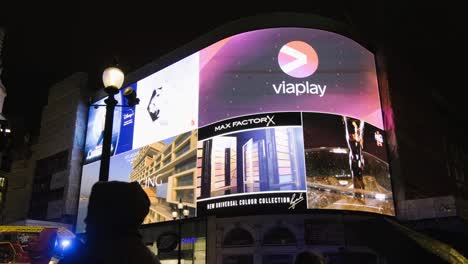 Encuadre-En-La-Pantalla-De-Piccadilly-Circus,-Que-Mira-A-La-Gente-Pasar,-En-El-Centro-De-Londres-Por-La-Noche.