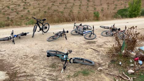 Many-mountain-bicycles-laying-on-the-ground-in-nature,-fun-day-out-on-bikes,-4K-shot