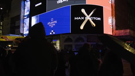 Pan-up-at-people-watching-Piccadilly-Circus-screen-in-central-London-at-night