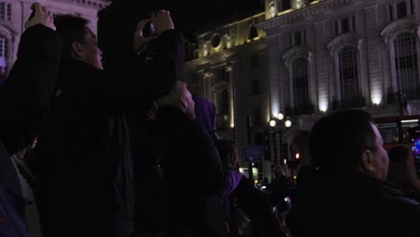Piccadilly-Circus-at-night-in-London-with-people-watching-and-recording-the-screen-on-their-phones