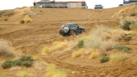 Video-De-Un-Automóvil-Que-Sube-Una-Colina-Empinada-En-Las-Dunas-De-Arena,-Mostrando-La-Velocidad-Y-La-Agilidad-Del-Automóvil-A-Medida-Que-Navega-Por-El-Terreno-Desafiante