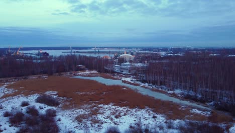 Daugavgriva-park-with-view-of-port,-blue-hour,-aerial-drone-view,-backwards