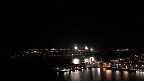 Firework-at-night-over-a-river,-with-port