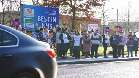 UK-hospital-nurses-protest-for-fair-pay,-holding-banners-and-flags-on-strike-during-cost-of-living-crisis