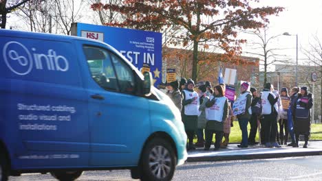 NHS-nurses-strike-for-fair-pay-and-better-care-outside-St-Helens-hospital-on-a-chilly-winter-morning,-waving-banners-and-flags