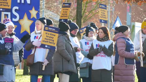 NHS-nurses-strike-protest-for-fair-pay-and-better-care-outside-hospital-on-a-chilly-winter-morning,-waving-banners-and-flags