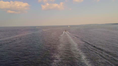 Following-a-single-boat-with-a-drone-over-the-ocean,-golden